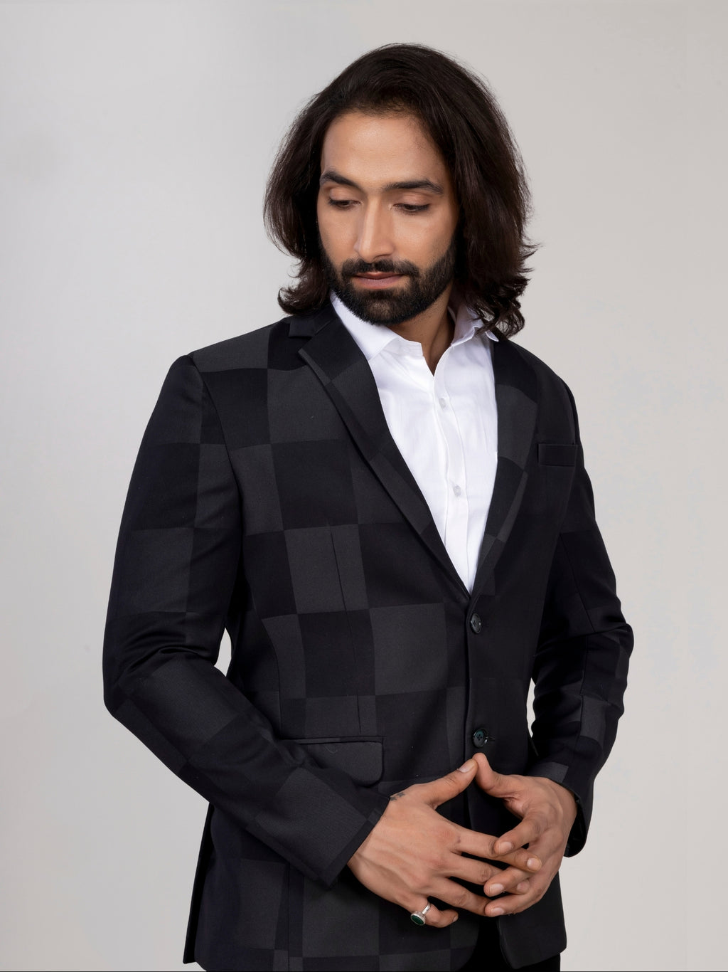 Man wearing a black checkered blazer over a white shirt on a plain background