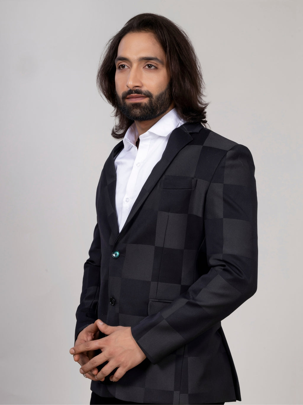 Man wearing a black checkered blazer over a white shirt on a gray background