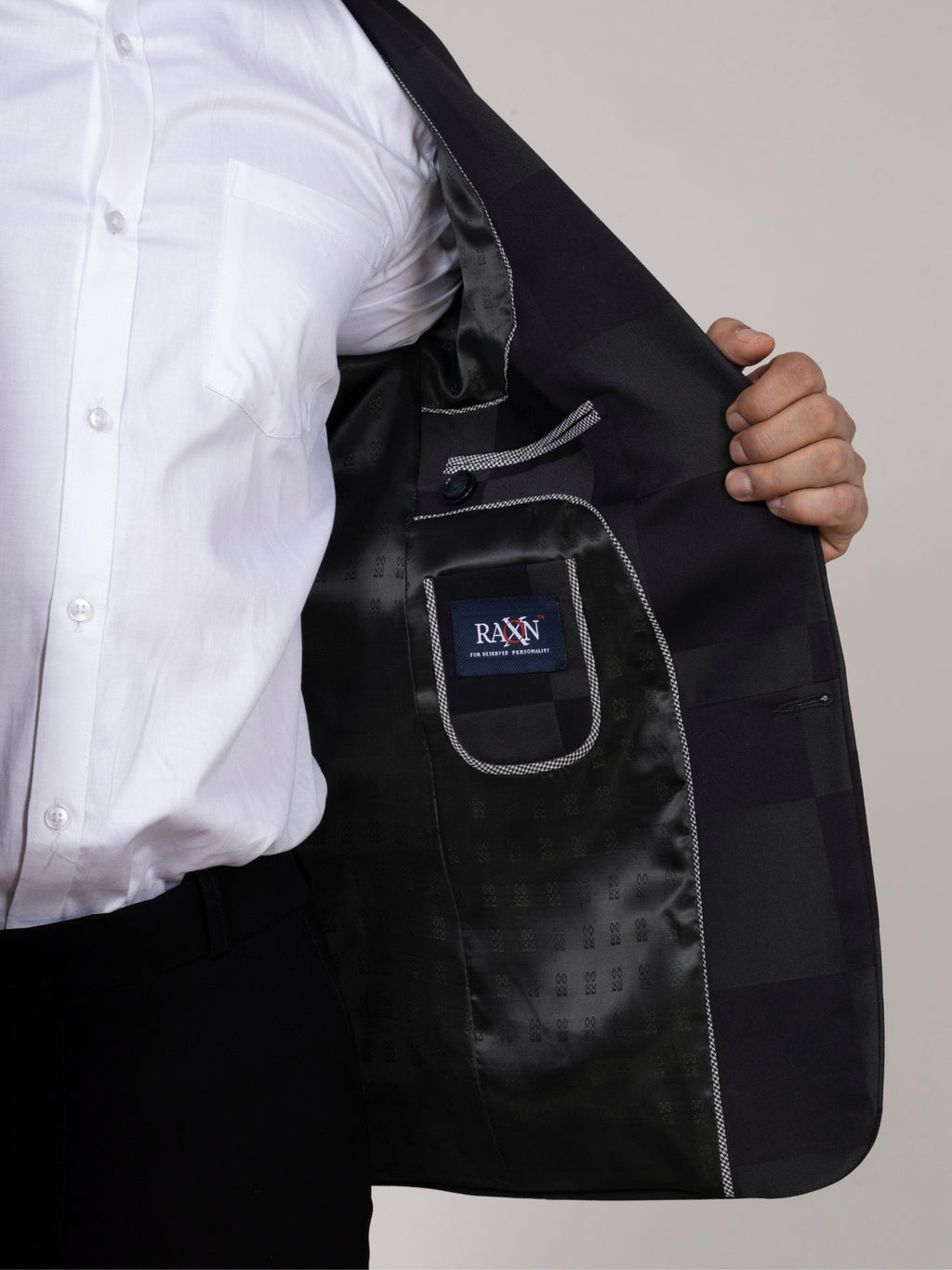 Black blazer with a visible brand logo over a white shirt on a neutral background