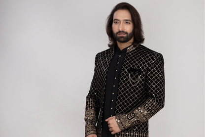 Man wearing a traditional embroidered sherwani with a vase of flowers in the background