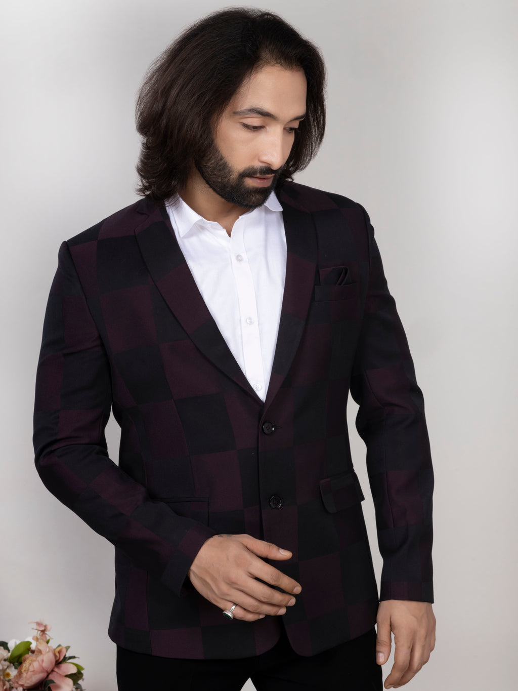 Man wearing a dark suit jacket over a white shirt against a plain background
