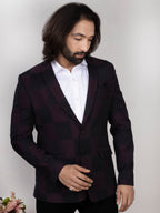 Man wearing a dark suit jacket over a white shirt against a plain background