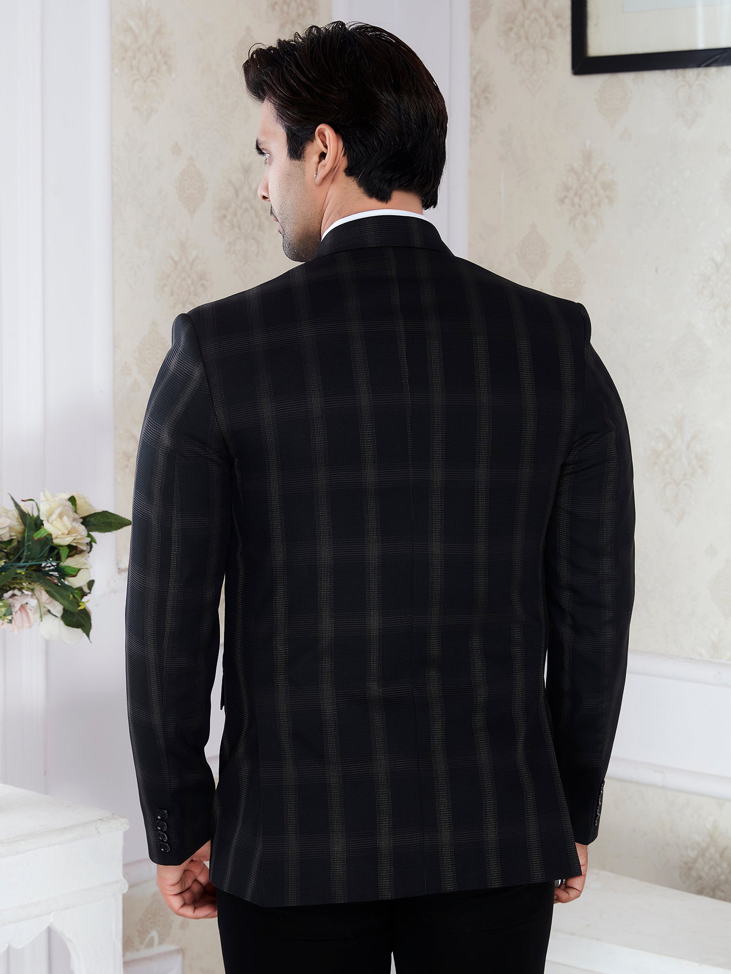 Man wearing a black checkered suit jacket in an indoor setting