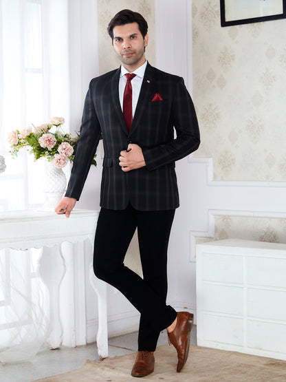 Man in a black pinstripe suit with a red tie standing in a room with white walls and a table with flowers.