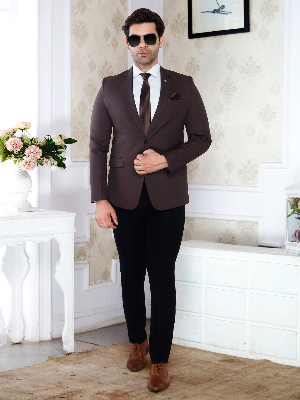 Man in a brown suit standing in a room with decorative elements.