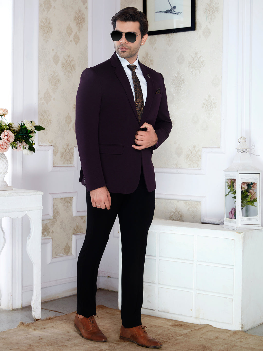 Man in a dark suit with sunglasses standing in a decorated room.