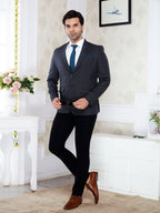 Man in a dark suit with a white shirt and brown shoes standing in a decorated room.