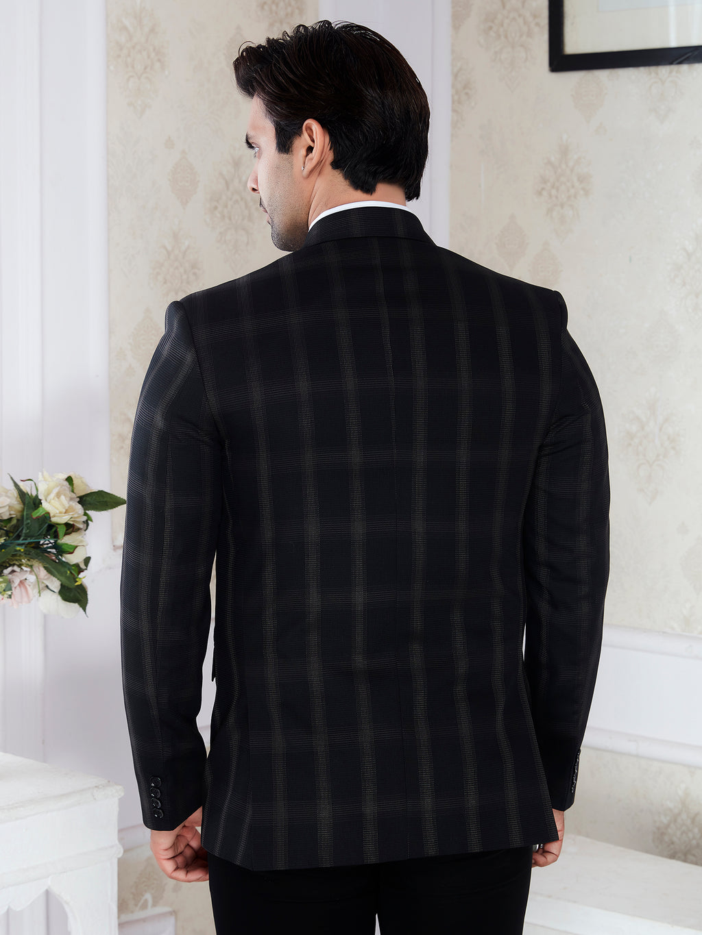 Man wearing a black checkered suit jacket in an indoor setting