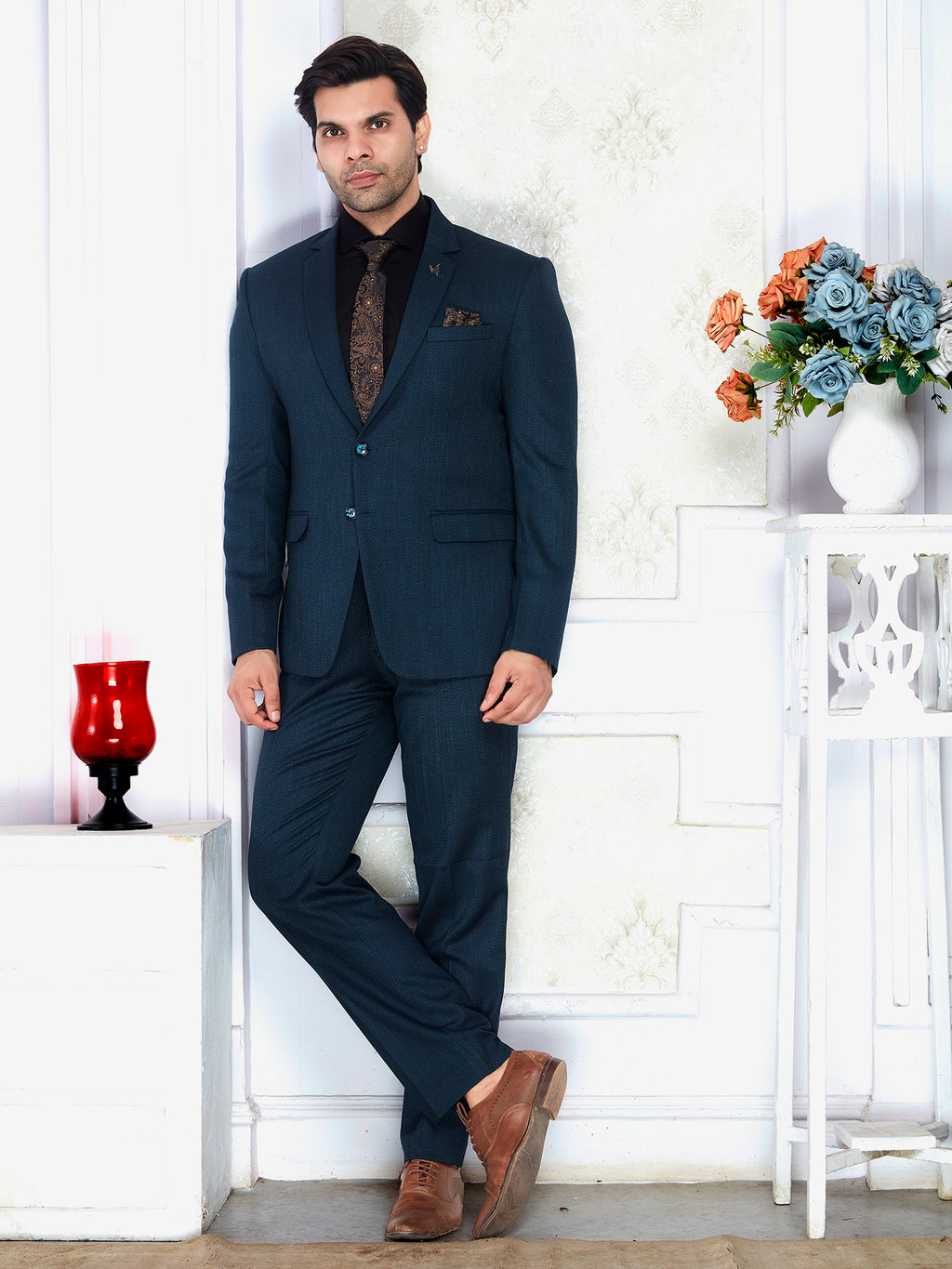 Man in a navy suit standing in a room with white walls and decorative elements.