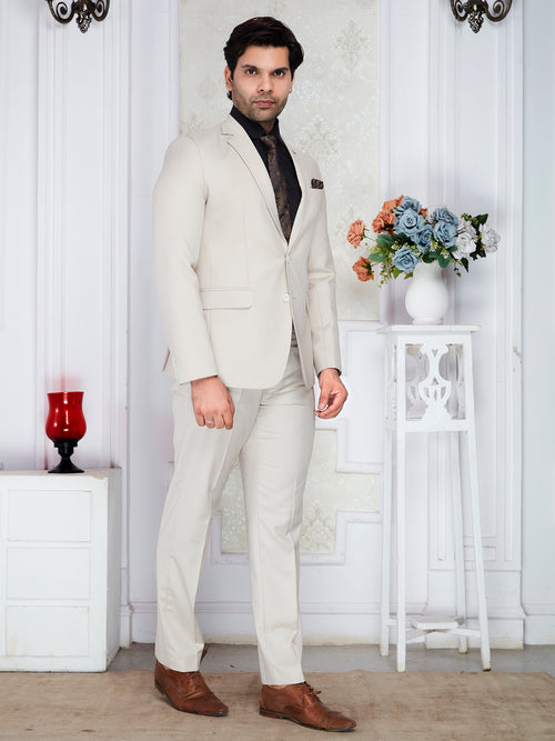 Man in a white suit standing in a room with decorative elements.